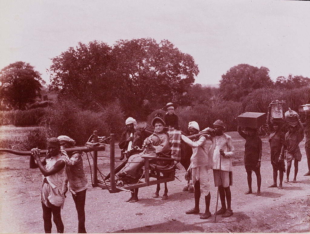 Several Sri Lankan men carry a white woman and boy in a litter, 1880s.