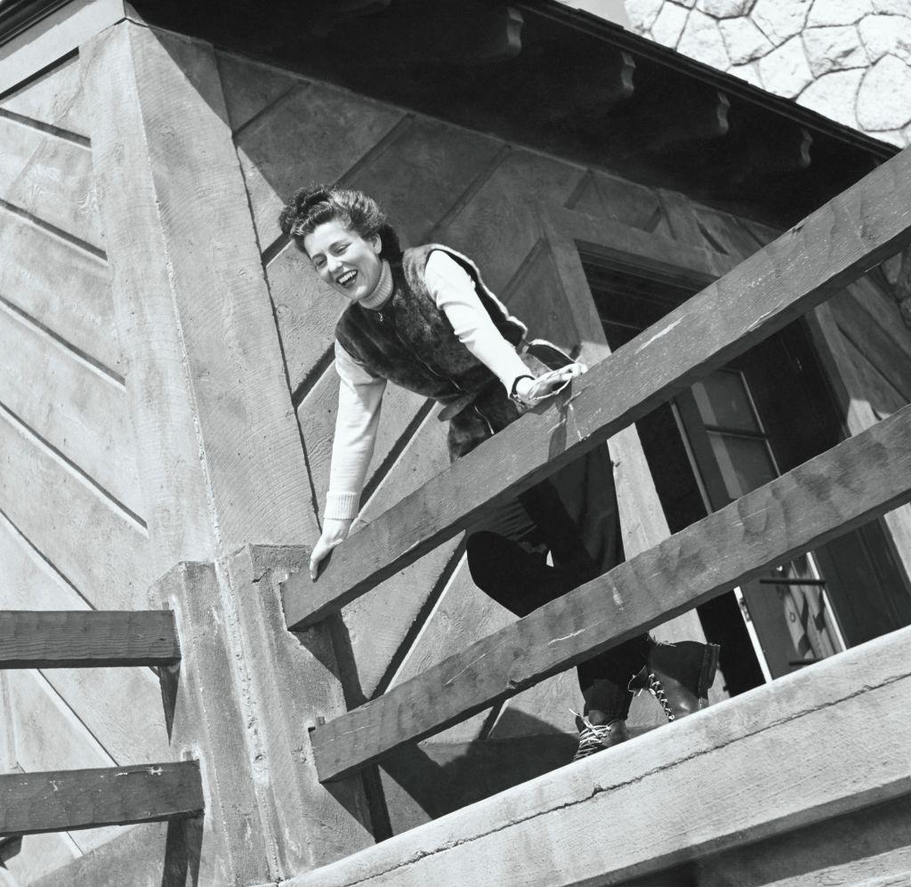 Mrs. Allan A. Ryan Jr., aka Eleanor Barry, leaning over the balcony railing of a chalet in Sun Valley, Idaho.