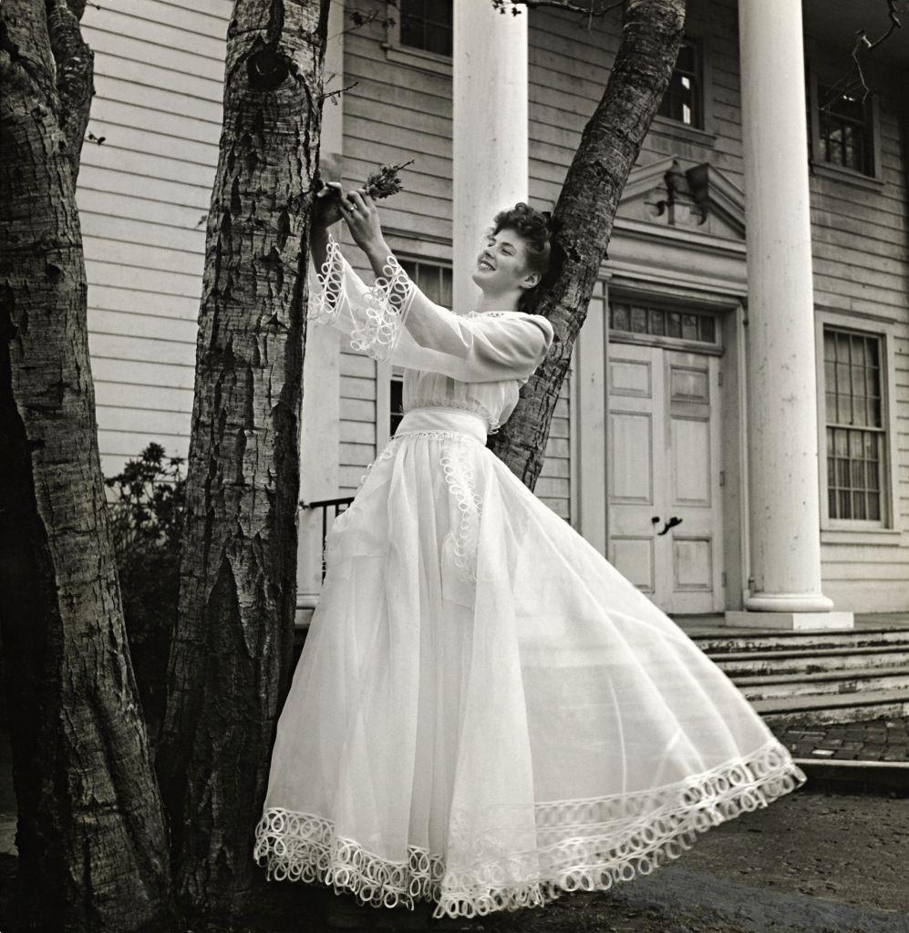 Actress Ingrid Bergman, leaning against a tree in front of a house, Vogue 1941.
