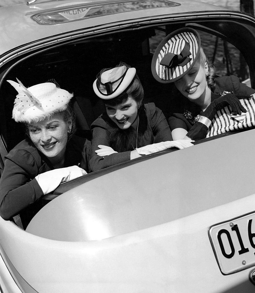 Three models looking out the back window of a car, Vogue 1941.