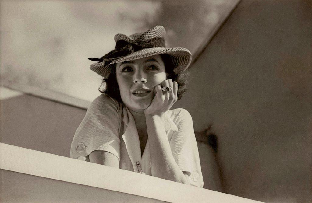 Model wearing a short-sleeved white rayon dress and a straw hat with a dented crown, Vogue 1934.