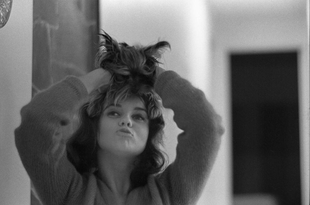 Ann-Margret playfully holding little dog on top of her head, 1963.