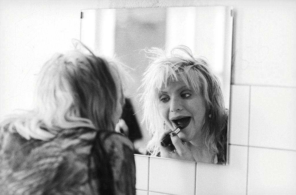 Courtney Love applies make-up in a mirror backstage before a concert at Rote Fabrik in Zurich, 1995.