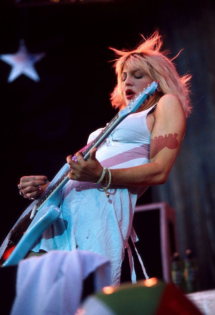 Courtney Love Playing guitar on stage.