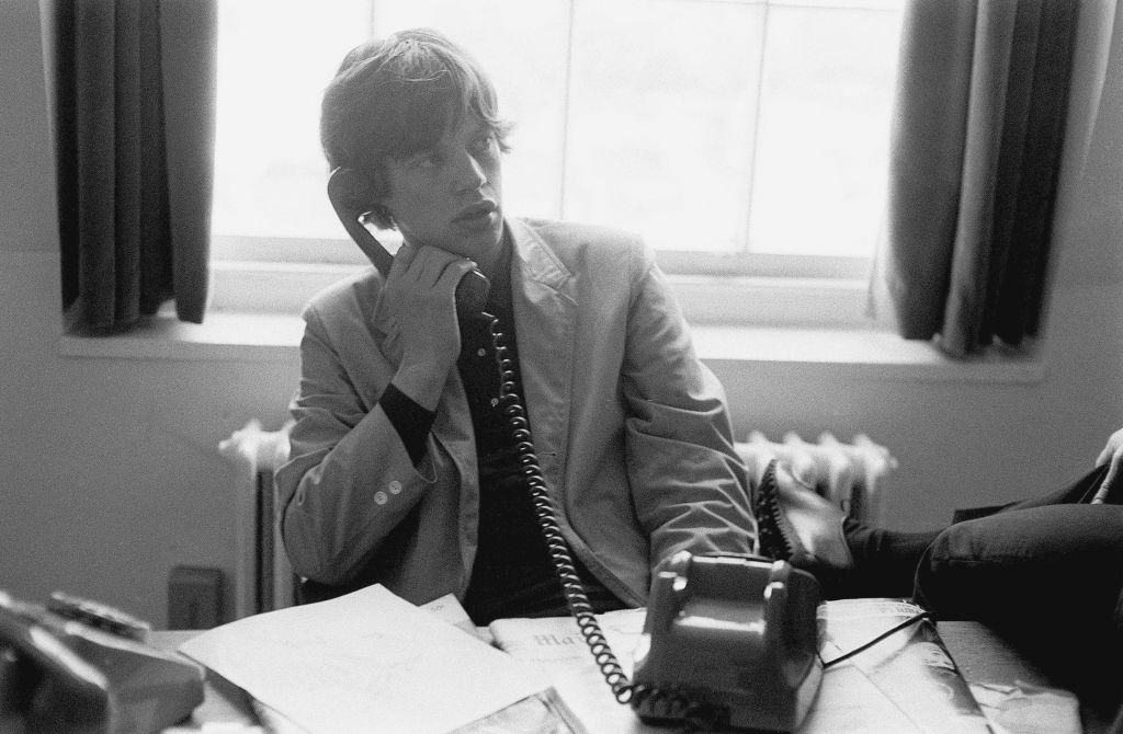 Mick Jagger takes a telephone call in an office, London, 1964.