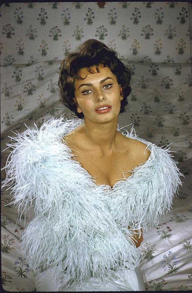 Sophia Loren wearing feather boa posing in her bedroom.