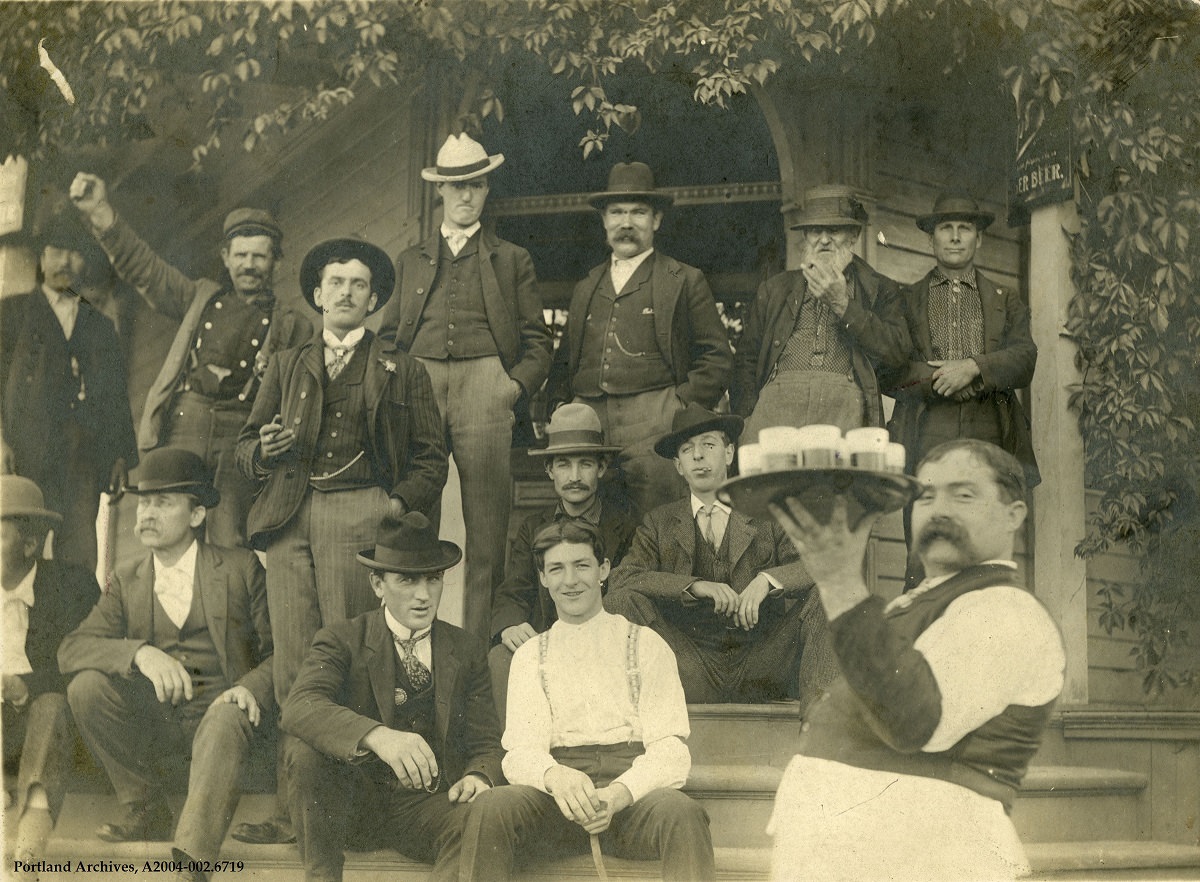 A group of men on the steps outside of Grohs Saloon, located on SW Macadam near the 7300 block, 1903.