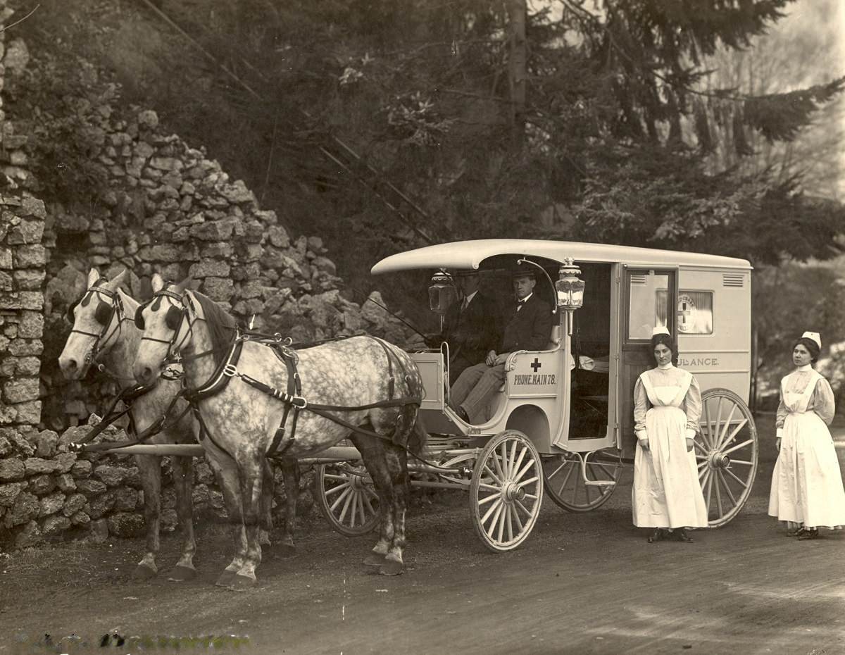 Two nurses and a driver pose with a Red Cross Service Ambulance, 1910.