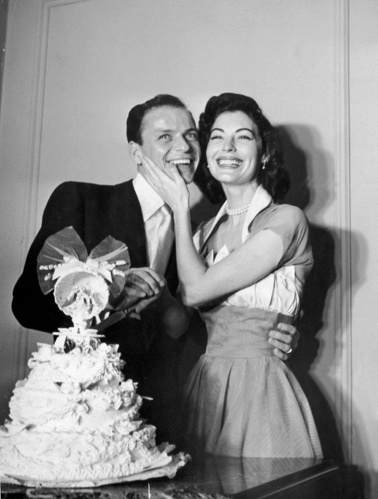 Frank Sinatra and Ava Gardner standing behind their wedding cake on their wedding day.