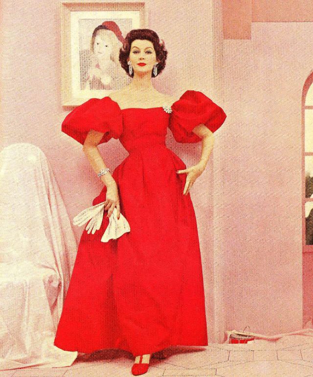 Dovima in a red taffeta evening gown with big poufy sleeves, and earrings, bracelet and brooch