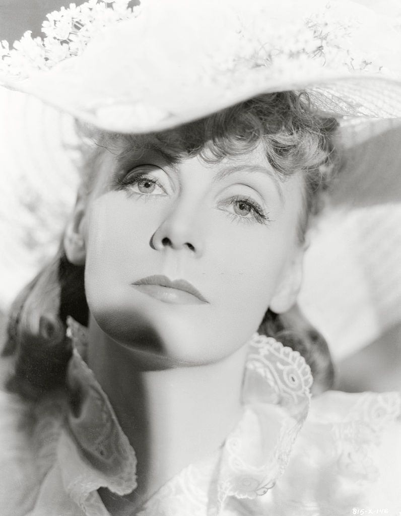 Greta Garbo in hat trimmed with small flowers.