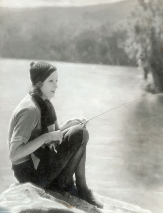 Greta Garbo posing with fishing rod in the outdoors, 1929.