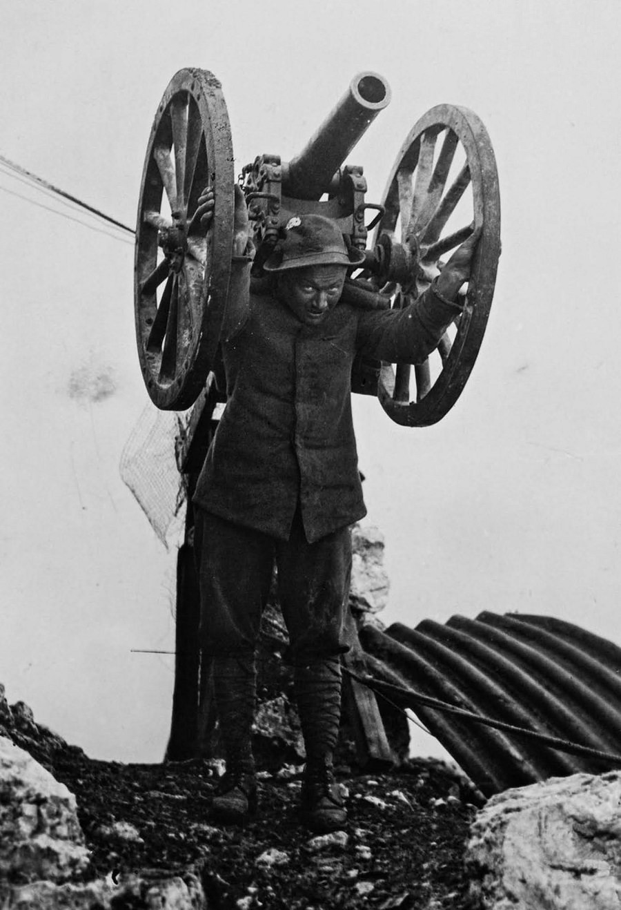A soldier carries a field gun to higher ground. 1916.