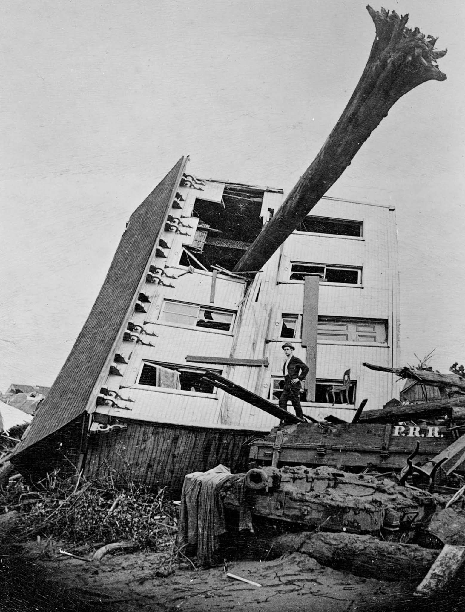 A tree protrudes from a house tossed by the flood.