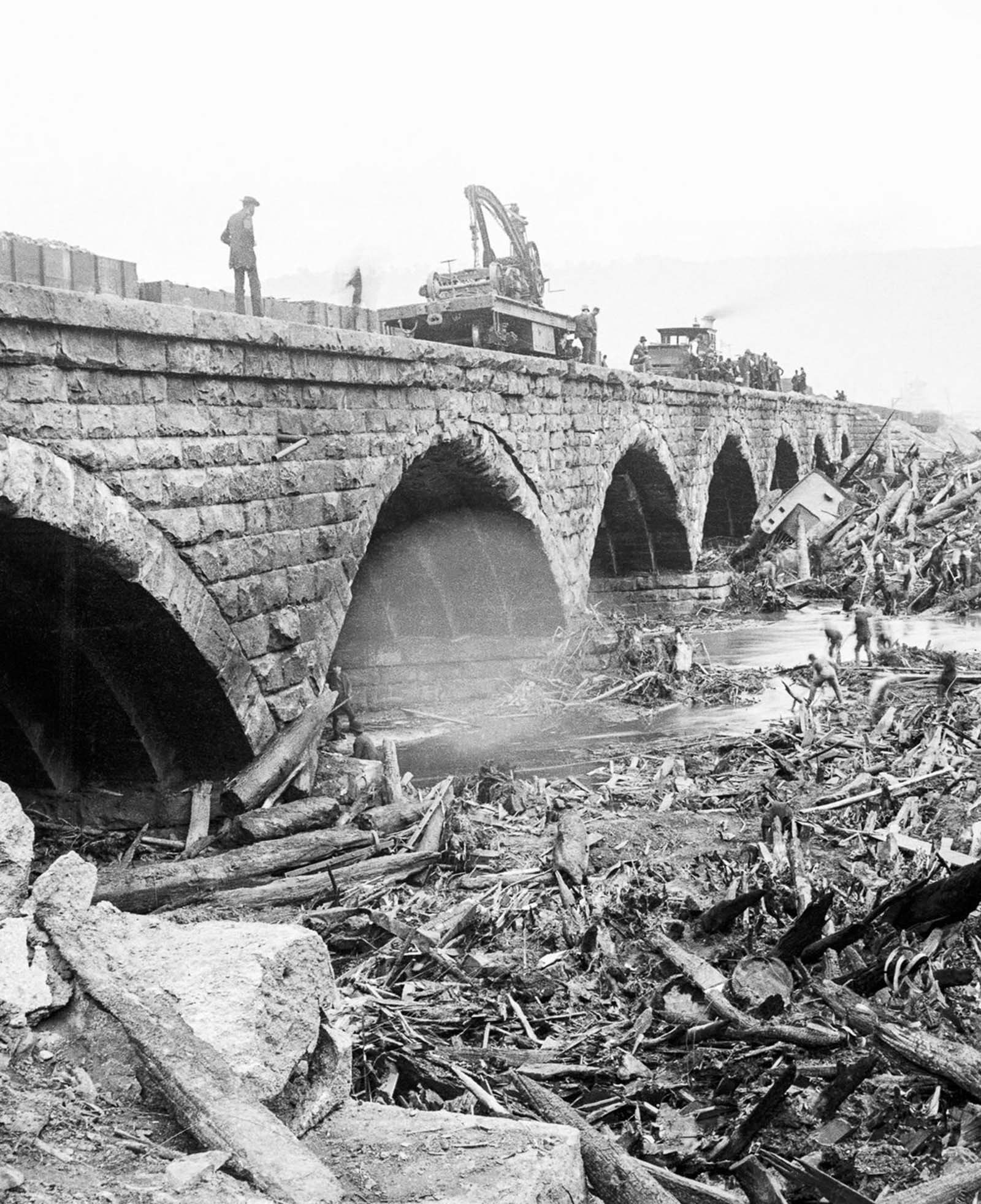 Volunteers search for bodies in the debris piled up against the stone bridge.