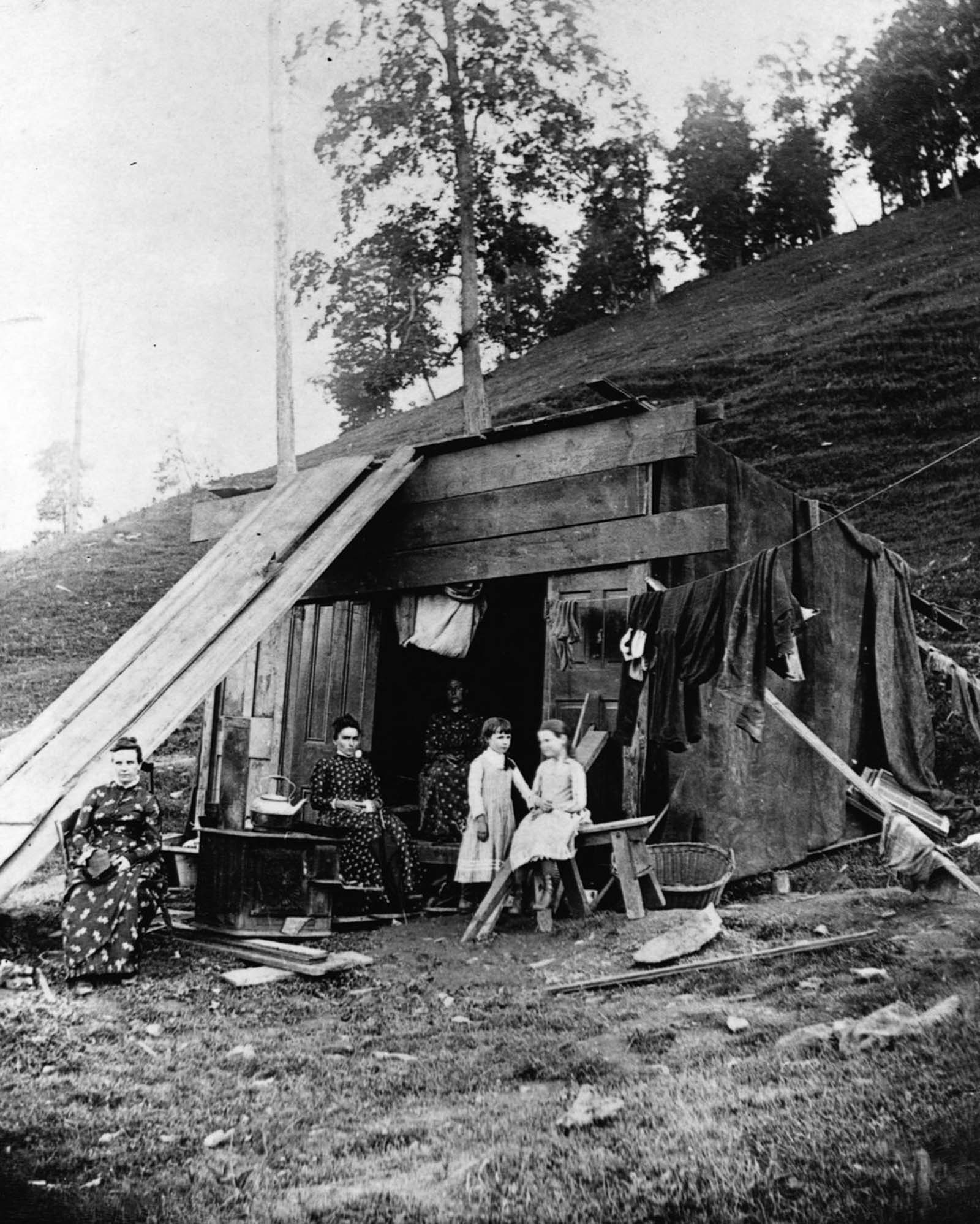 A family of survivors lives in a makeshift shelter in a cave.