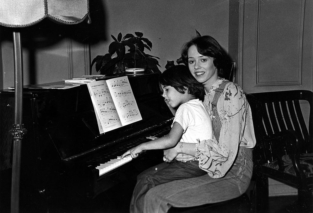 Mackenzie Phillips with a baby at the piano on December 3, 1976