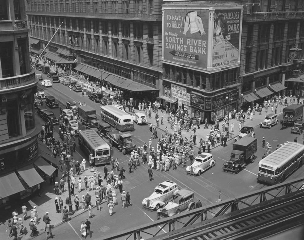 Looking down from ‘el’ station at intersection of 34th and Broadway; pedestrians, traffice, Macy’s and billboards, Saks at 34th St.