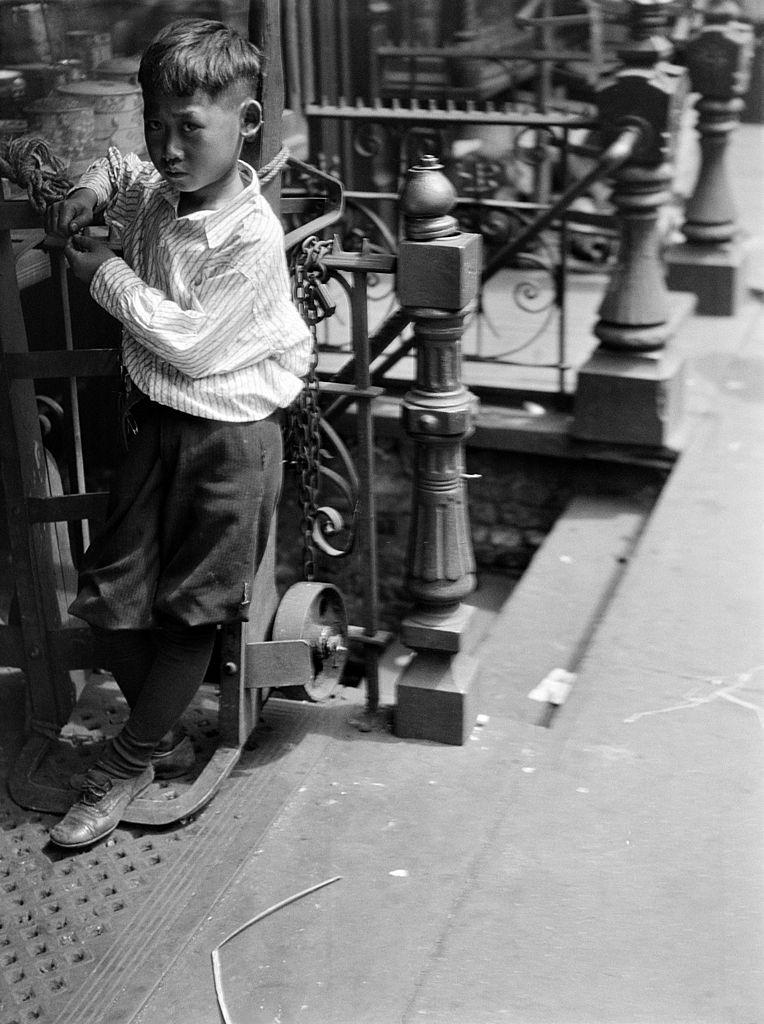 A young Chinese boy standing on a dolly, New York City, 1930.