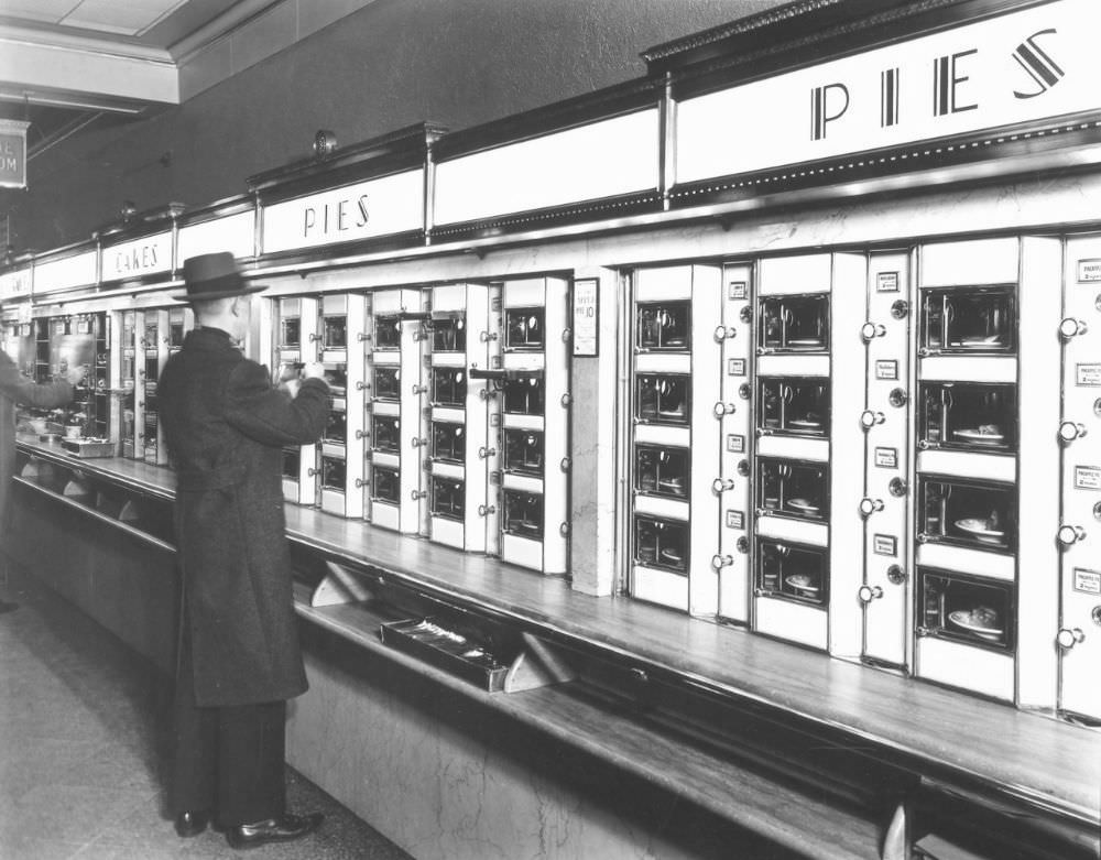 Automat, 977 Eighth Avenue, Manhattan. Man takes pie out of Automat, stone counters and walls below metal and glass display.