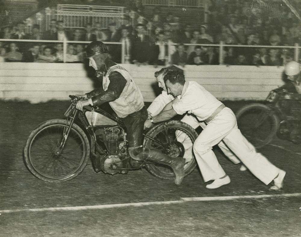 Motor bike racer getting a push start at the track, Brisbane, 1955.