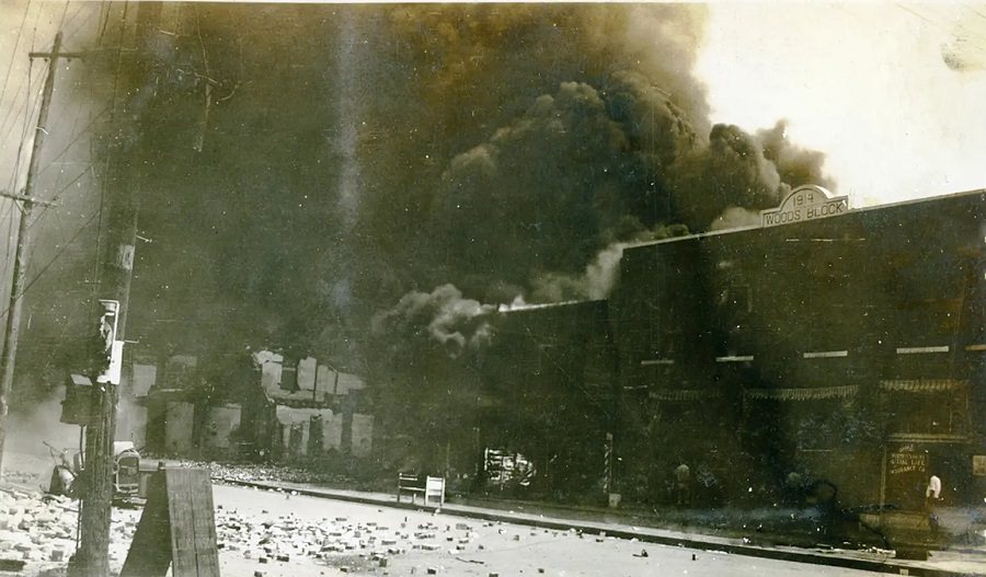 Clouds of black smoke rise over the rubble of buildings destroyed in the Tulsa massacre in June 1921.