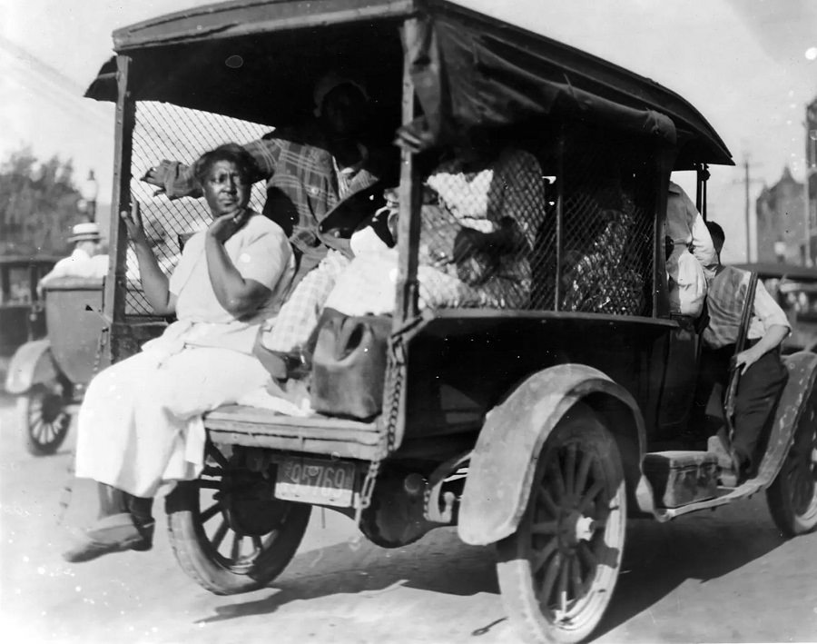 Detained residents are transported in Tulsa in June 1921. A man holding a rifle sits on the running board.