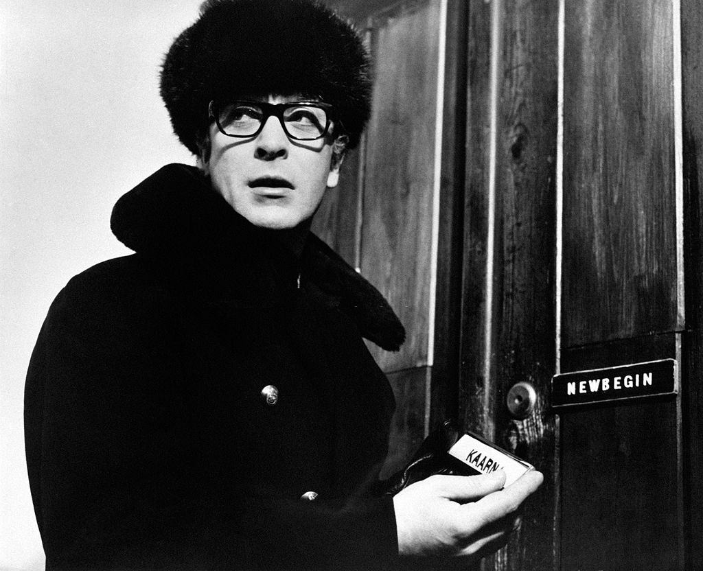 Michael Caine in front of a door with a plate in the hand in the film Billion Dollar Brain, 1967.