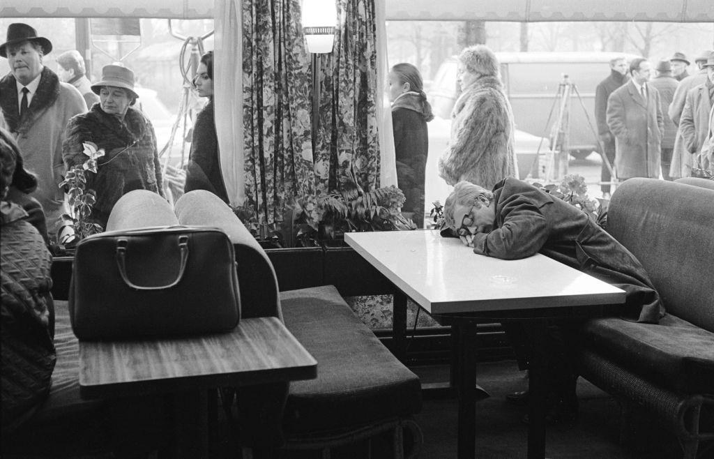 Michael Caine asleep in a cafe with his head resting on the table, 1965.