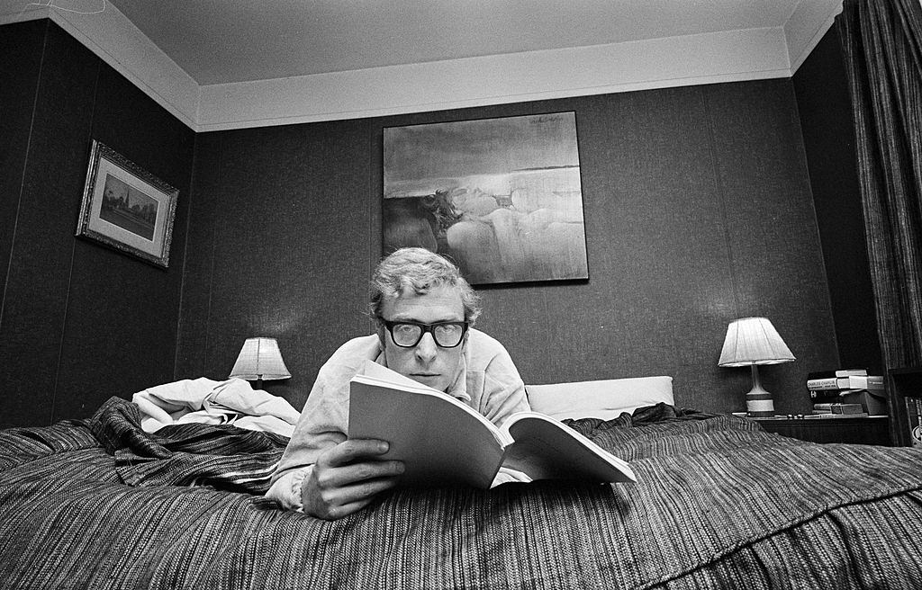 Michael Caine lying on his bed at home reading a book, in London, 1965.