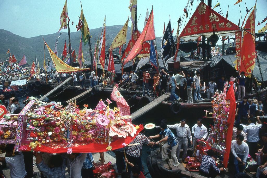 Celebrants carry paper shrines from boats to temple on Po Toi Island during festival dedicated to Goddess of Sailors and the Sea. Hong Kong, 1980s.