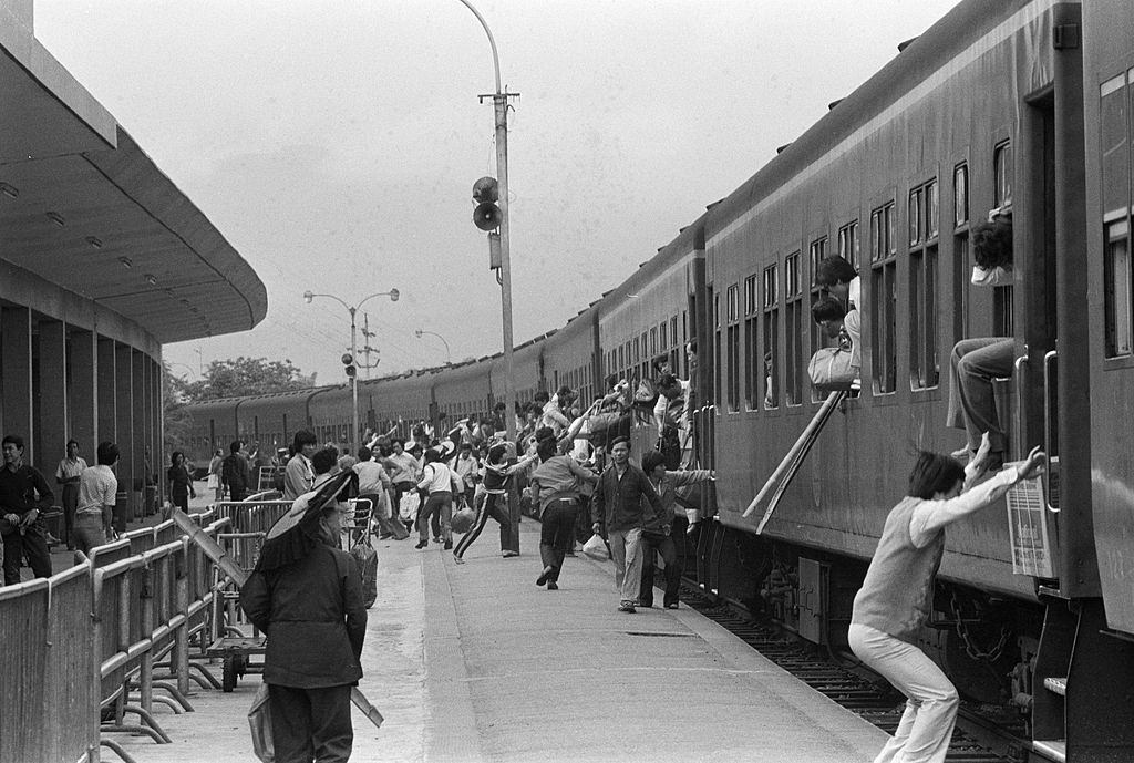 Travelers rush along the wagons on the platform, also passing through the windows.Hong Kong 1981.