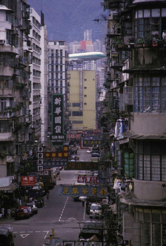 A plane flying very close to the tops of buildings before landing at Kai Tak airport in Hong Kong, circa 1980