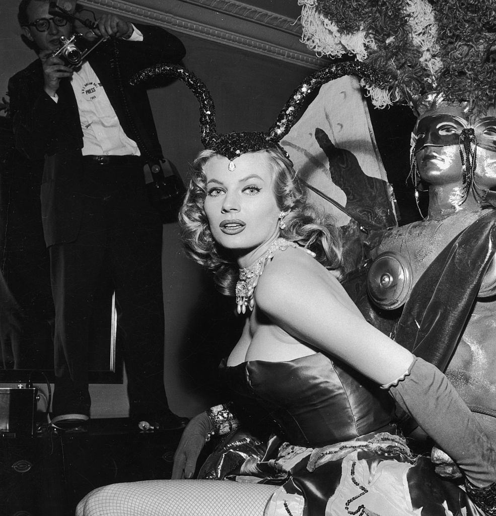 Anita Ekberg poses in a strapless costume with fishnet stockings and a sequined headdress, 1955.
