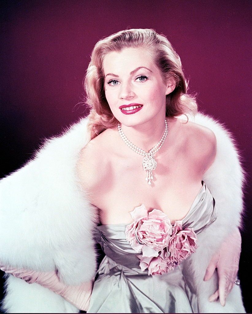 Anita Ekberg wearing a glamorous in a low-cut dress, with flowers covering her cleavage, 1956.