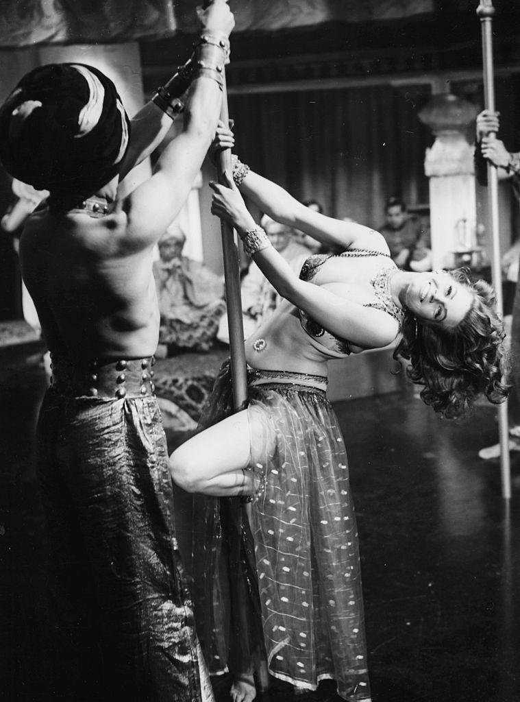 Anita Ekberg dancing on a pole during a scene from the movie 'Zarak'.