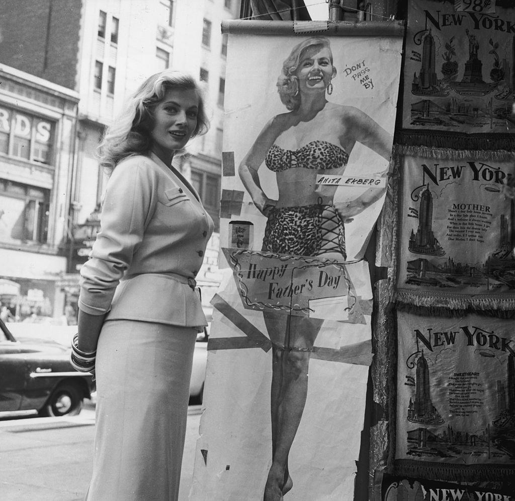 Anita Ekberg poses next to a full-length poster, 1958.