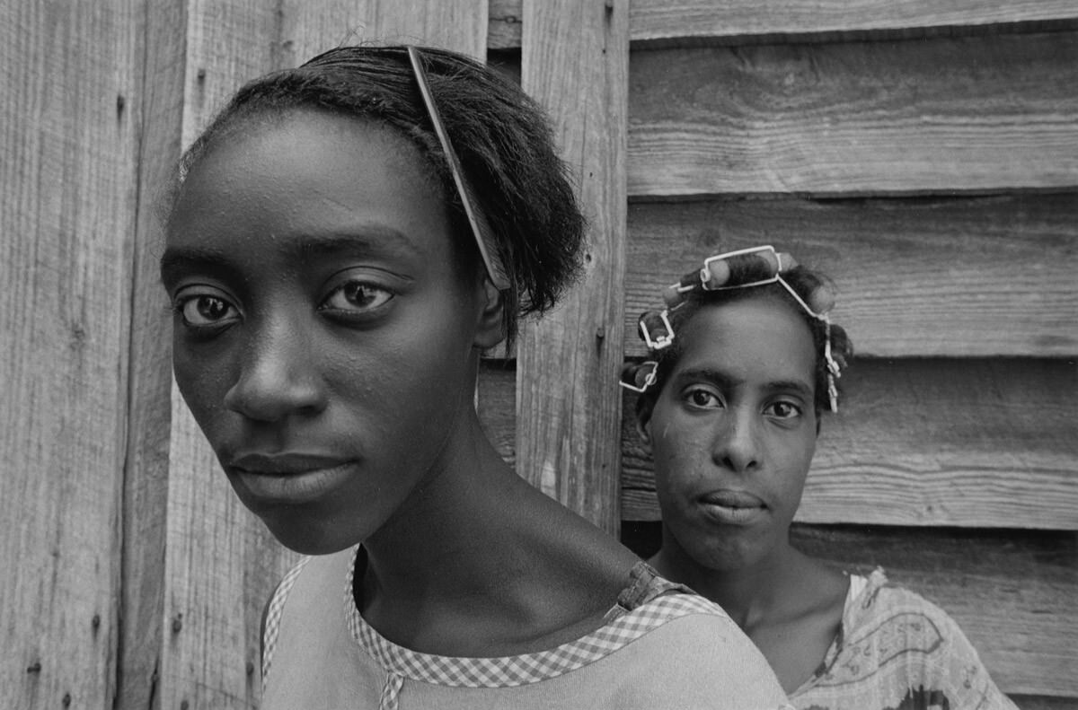 Two women (head shot) in front of tobacco barn, 1966