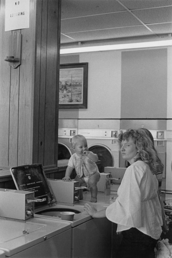 Woman and baby in laundromat in Bainbridge Mall, 1973