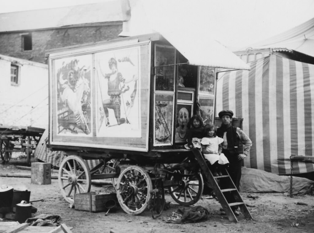 Two children and a man sitting on the steps of a caravan, Buff Bill's Circus. 1910.