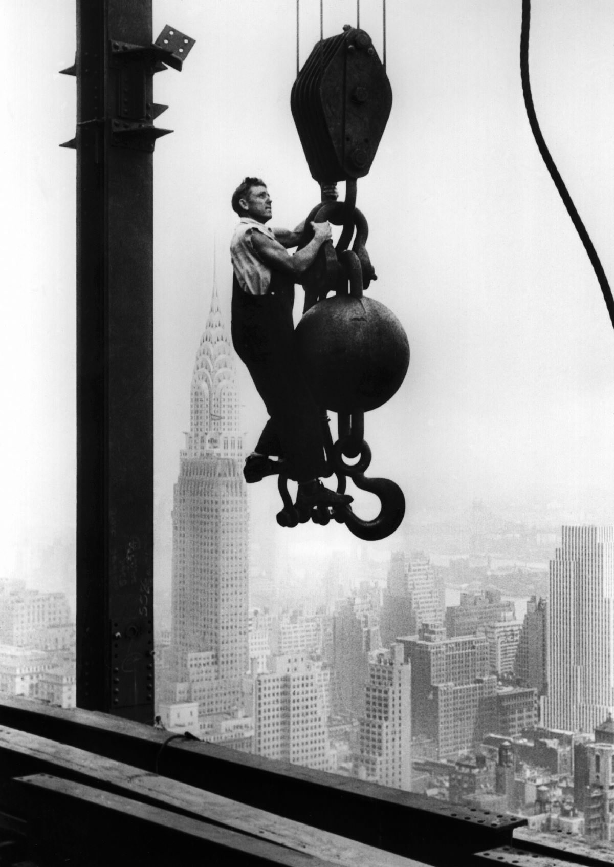 A construction worker hangs from an industrial crane during the construction of the Empire State Building. Oct. 29, 1930