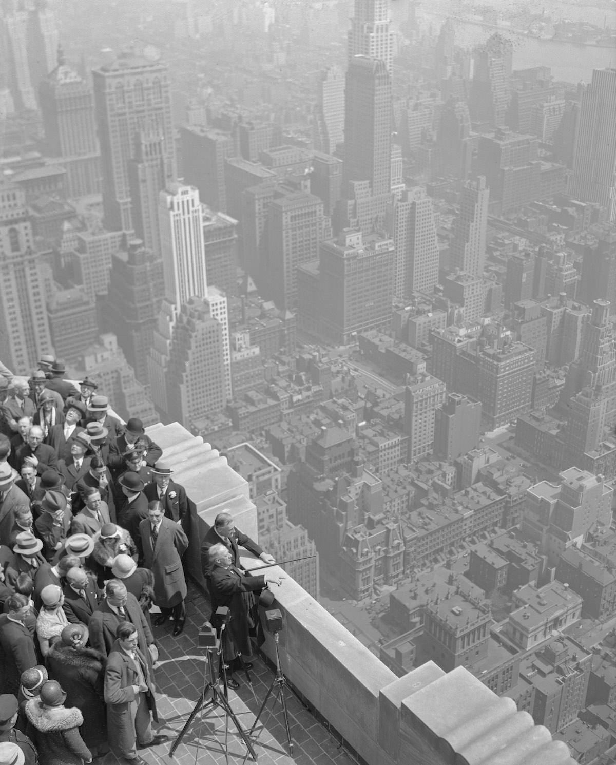Ex-Governor Alfred E. Smith, Governor Franklin D. Roosevelt, and others at the top of the Empire State Building, tallest in the world, gazing out over the New York panorama.