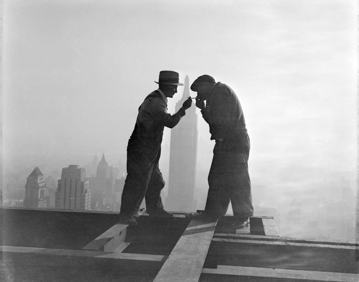 New York City: Lighting Up 'Way Up.' A striking silhouette atop the gigantic RCA Building in Rockefeller Center, New York, as workmen light their cigarettes at the end of a working day.
