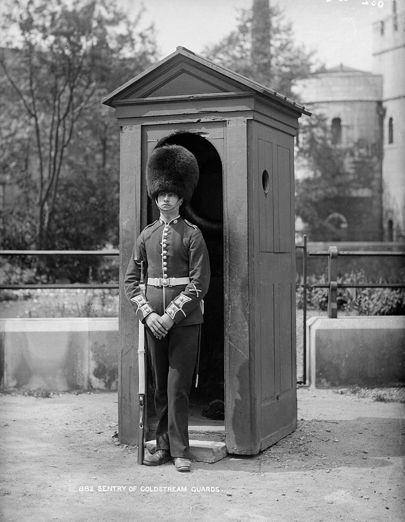 A Coldstream Guardsman at his sentry box, outside the Tower of London. 1903.