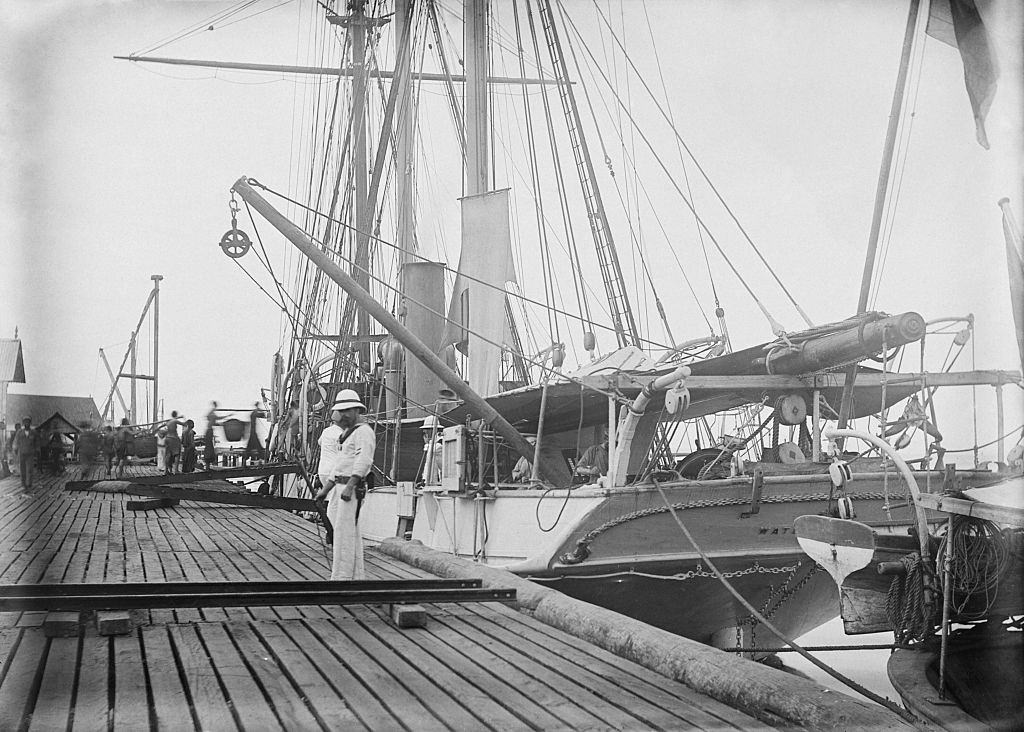 Royal Navy ship HMS Waterwitch anchored of Labuan Asian coast as a group of chinese convicts load sacks of coal.