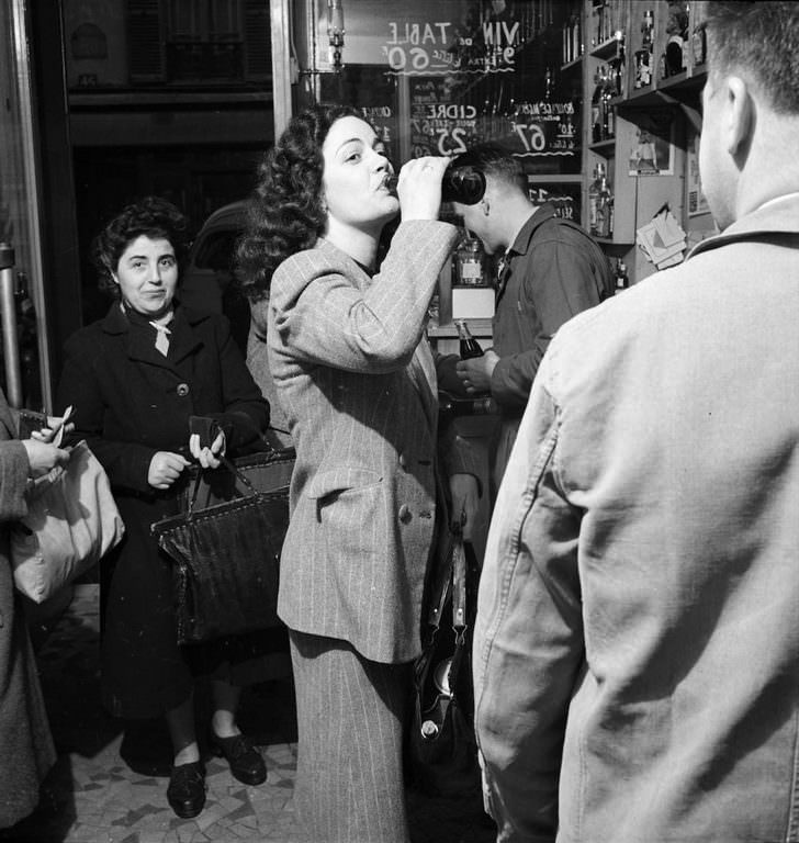 A young woman drinks a bottle of Coca-Cola in a Paris shop.