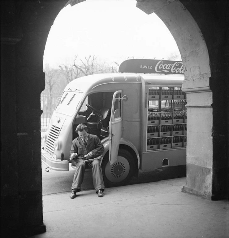 A Coca-Cola delivery driver sits in the open door of his truck while on a break, in France.