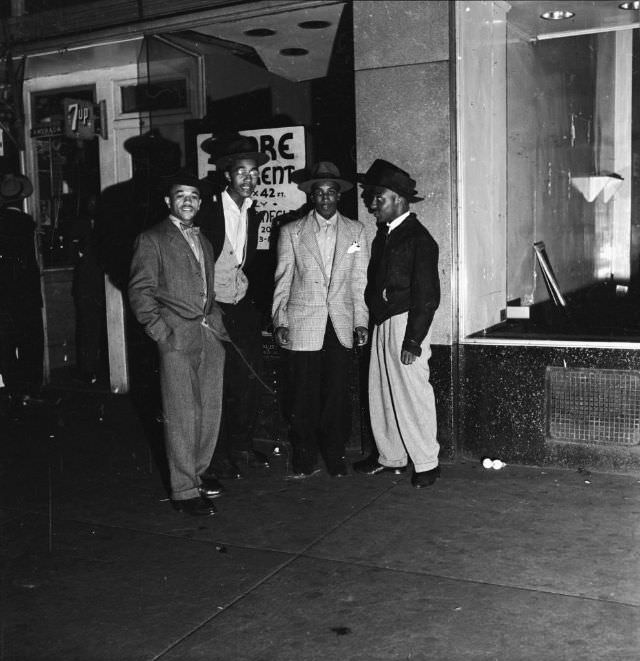 A group of affluent men standing on the street at night, 1942.
