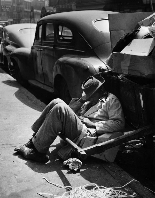 A man takes a nap against a handcart, 1948.
