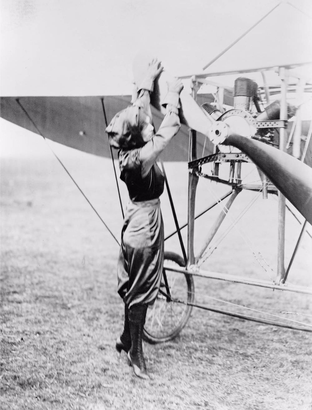 Harriet Quimby, wearing her purple satin flying suit, pulls the Chauvière Intégrale propeller of the Blériot XI to start the air-cooled Anzani W3 (“fan” or “semi-radial”) three-cylinder engine.